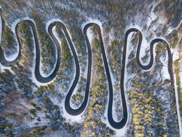 Winding road through the forest, from high mountain pass, in winter time